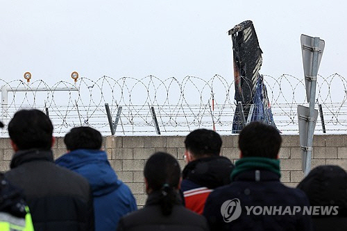 제주항공 참사 2주째인 11일 무안국제공항에서 유가족들이 사고 현장을 찾아 기체를 바라보고 있다.  [연합뉴스]